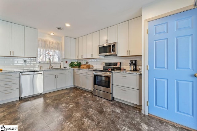 kitchen with stainless steel appliances, visible vents, decorative backsplash, white cabinetry, and a sink