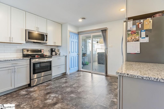 kitchen featuring light stone counters, visible vents, backsplash, appliances with stainless steel finishes, and white cabinetry