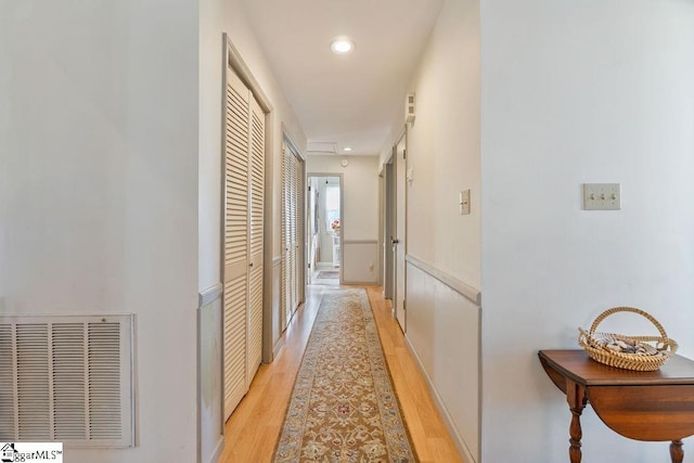 hallway with light wood-type flooring, visible vents, and recessed lighting