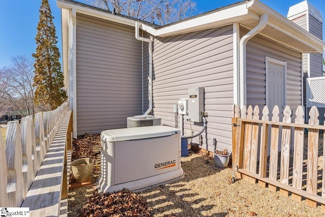 view of side of home with fence, a chimney, and central AC unit