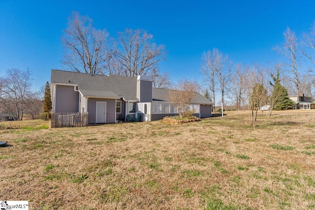 back of property with a garage, a chimney, and a yard