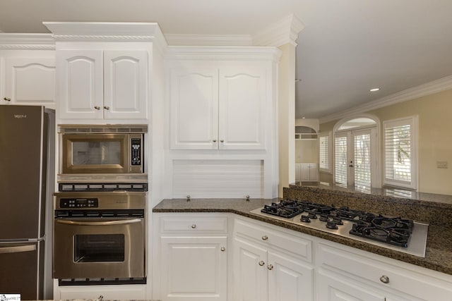 kitchen with crown molding, recessed lighting, appliances with stainless steel finishes, white cabinetry, and dark stone countertops