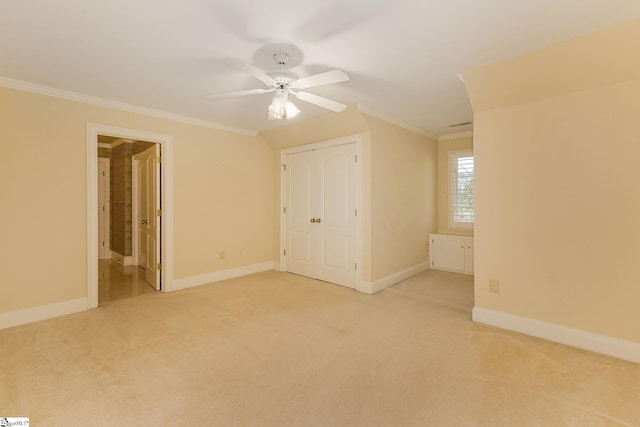 unfurnished bedroom featuring baseboards, ornamental molding, a ceiling fan, and light colored carpet