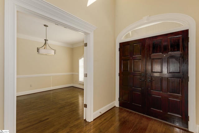 foyer entrance with dark wood-style floors, baseboards, and ornamental molding