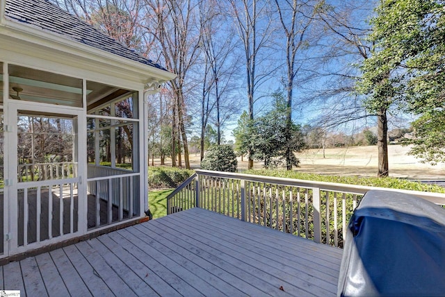 wooden deck featuring a sunroom and a grill