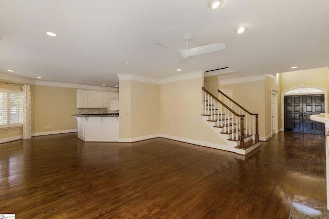 unfurnished living room with recessed lighting, stairway, dark wood-type flooring, ornamental molding, and baseboards