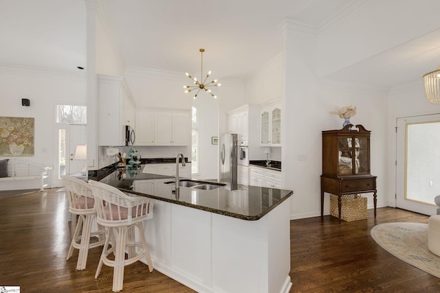 kitchen featuring stainless steel appliances, dark wood finished floors, a sink, and a peninsula