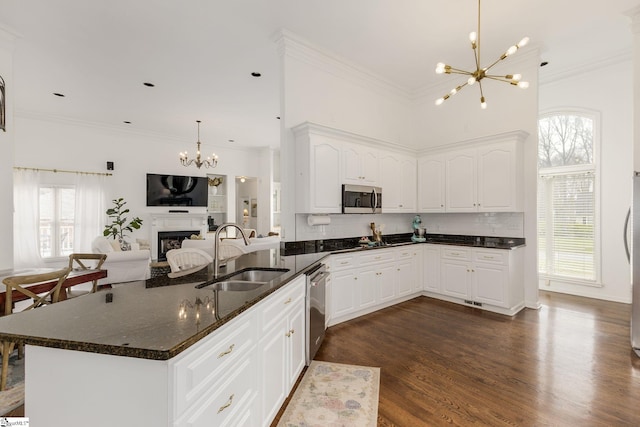 kitchen with a fireplace, stainless steel appliances, an inviting chandelier, ornamental molding, and a sink