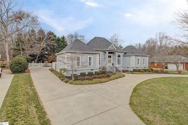 view of front of home with a chimney, fence, a front lawn, and concrete driveway