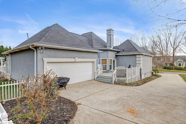 rear view of house featuring a garage, roof with shingles, fence, and stucco siding