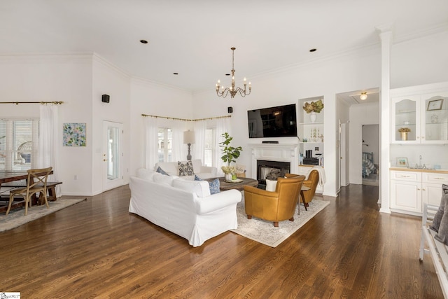 living area with crown molding, dark wood finished floors, a chandelier, and a fireplace