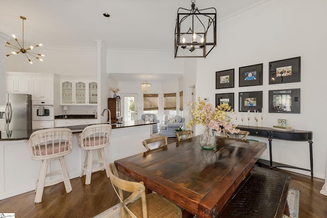 dining space with an inviting chandelier, ornamental molding, and dark wood finished floors