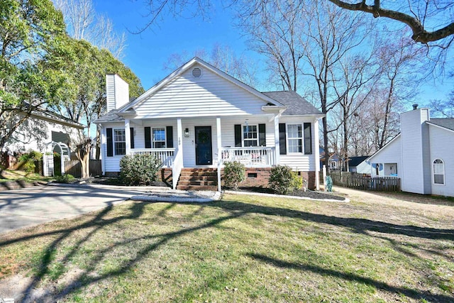 bungalow-style home featuring a chimney, covered porch, a front yard, crawl space, and fence