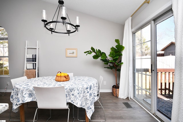 dining area with baseboards, dark wood finished floors, visible vents, and an inviting chandelier