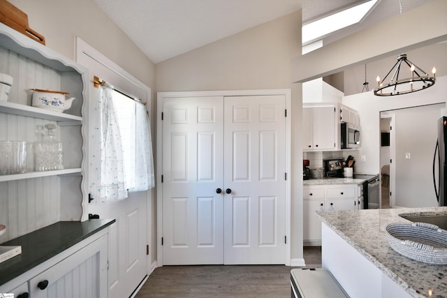 kitchen featuring dark wood-style floors, a notable chandelier, stainless steel appliances, lofted ceiling, and white cabinets