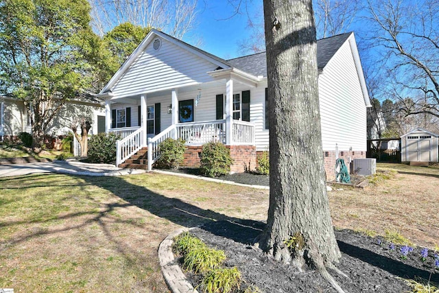 view of front of property with central air condition unit, covered porch, a shed, an outdoor structure, and a front lawn