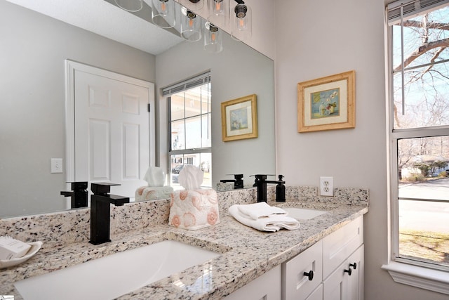 bathroom with double vanity, a sink, and a healthy amount of sunlight