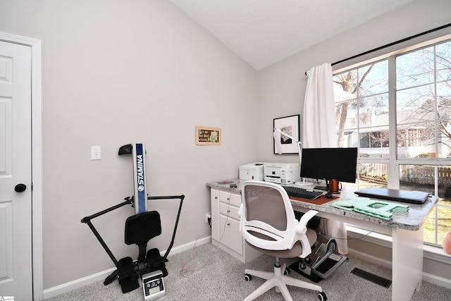 office area with visible vents, baseboards, vaulted ceiling, and light colored carpet