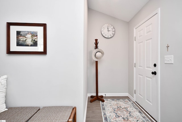 entryway with vaulted ceiling, wood finished floors, and baseboards