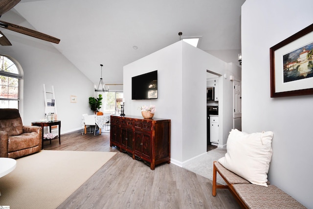 interior space with baseboards, a chandelier, vaulted ceiling, and wood finished floors