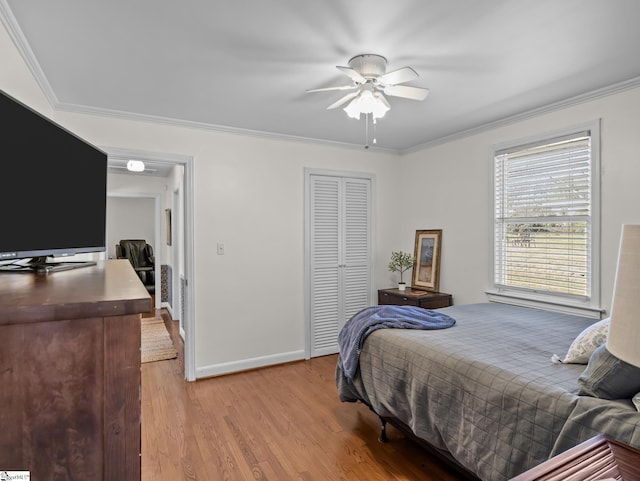 bedroom featuring light wood-style flooring, a closet, baseboards, and crown molding