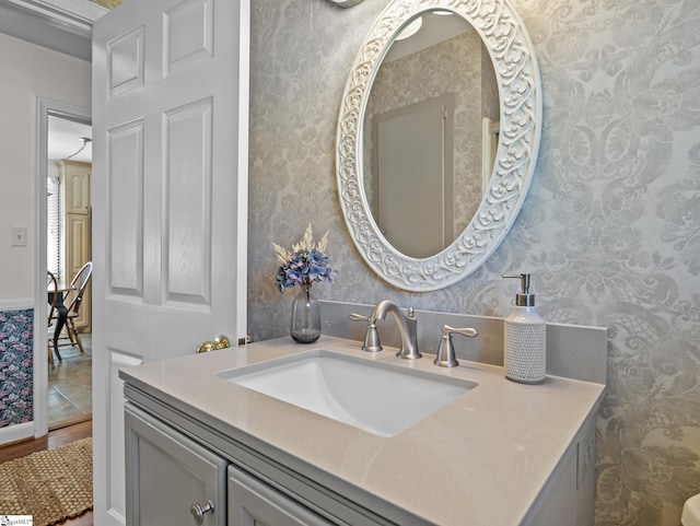 bathroom featuring wood finished floors, vanity, and wallpapered walls