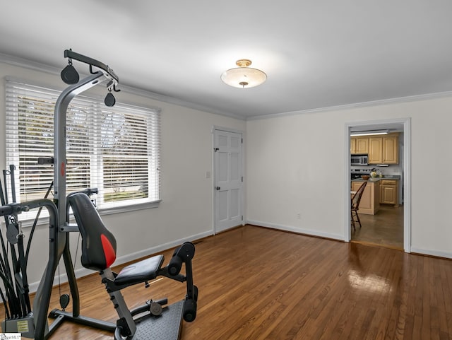 workout area with ornamental molding, wood finished floors, and baseboards