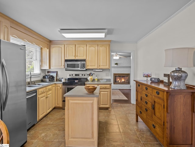 kitchen with a center island, crown molding, light brown cabinetry, appliances with stainless steel finishes, and a sink