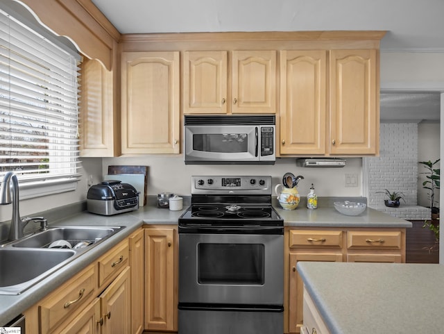 kitchen featuring light countertops, stainless steel appliances, a sink, and light brown cabinetry