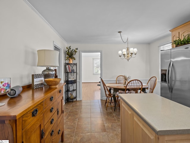 interior space with a notable chandelier, a center island, wood counters, stainless steel fridge with ice dispenser, and tile patterned floors