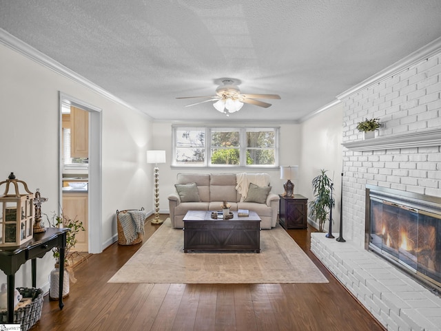 living room with a textured ceiling, a fireplace, dark wood finished floors, and crown molding