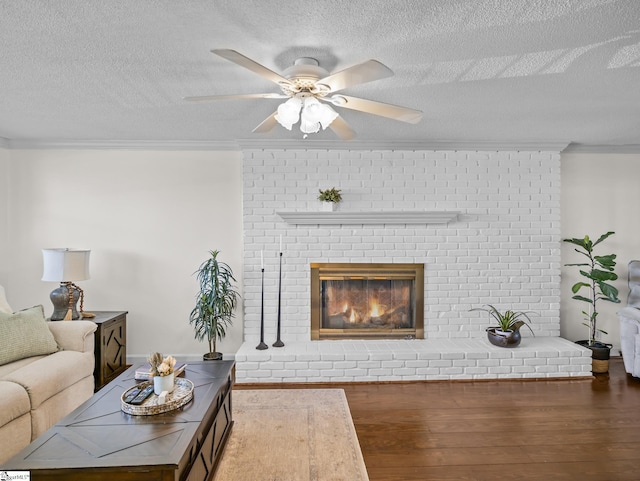 living room featuring ornamental molding, a brick fireplace, wood finished floors, and a ceiling fan