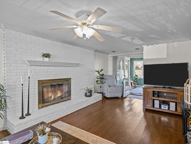 living room featuring a textured ceiling, a brick fireplace, hardwood / wood-style flooring, and crown molding