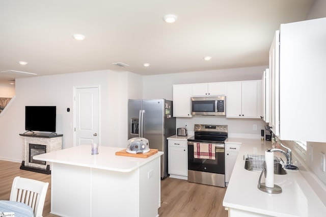 kitchen with light countertops, appliances with stainless steel finishes, white cabinets, and light wood-style floors