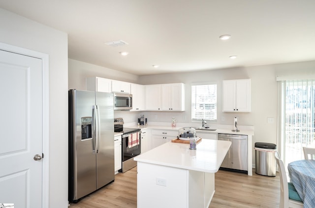 kitchen featuring stainless steel appliances, a wealth of natural light, light wood-type flooring, and a sink