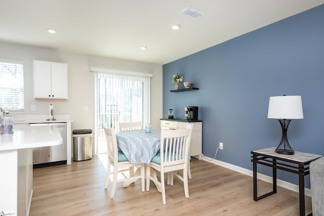 dining area with light wood-style flooring, plenty of natural light, visible vents, and baseboards