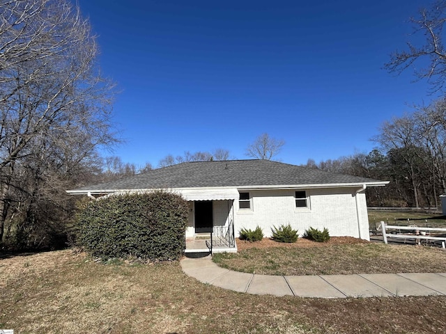 view of front of house with roof with shingles, a front lawn, and brick siding