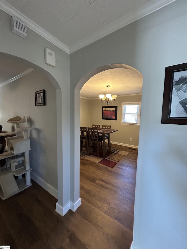 hallway featuring ornamental molding, arched walkways, dark wood-style flooring, and baseboards