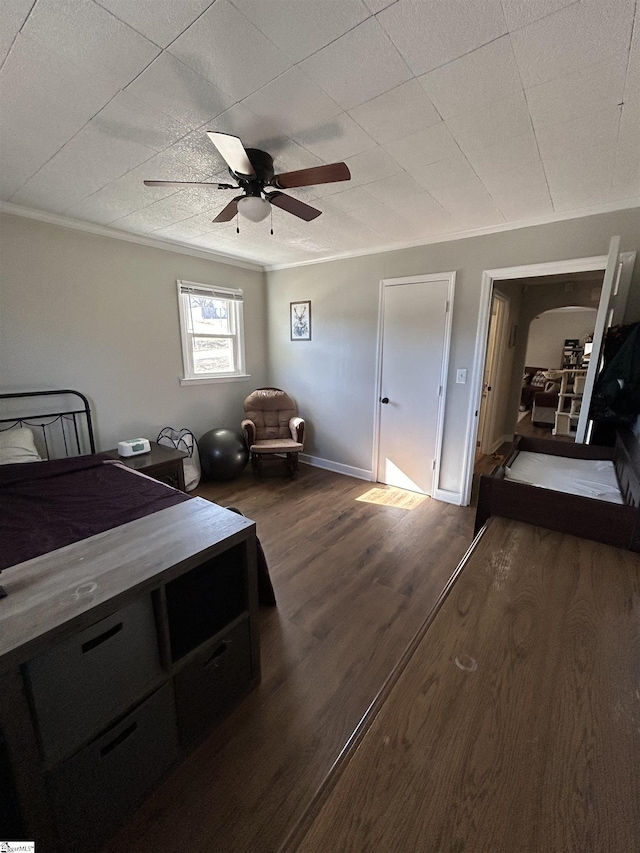 bedroom with ornamental molding, dark wood-style flooring, ceiling fan, and baseboards