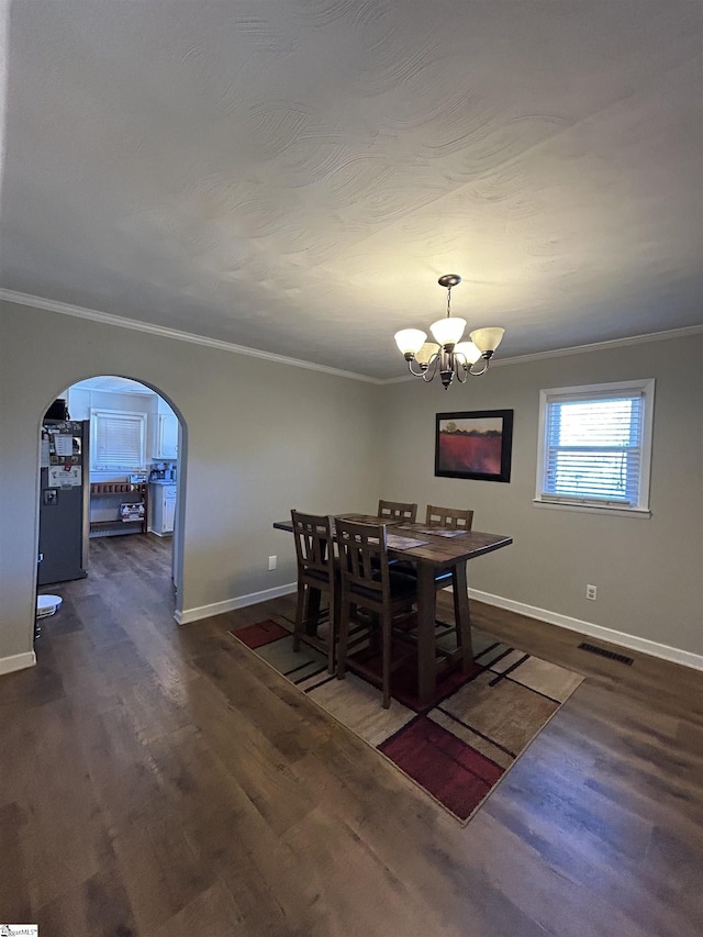 dining space with visible vents, arched walkways, wood finished floors, and ornamental molding