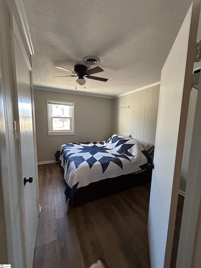 bedroom with a ceiling fan, a textured ceiling, visible vents, and dark wood-style flooring