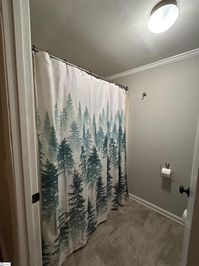 bathroom featuring toilet, a shower with curtain, baseboards, and ornamental molding