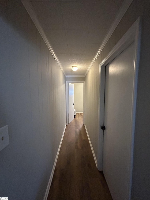 corridor featuring dark wood-type flooring, crown molding, and baseboards