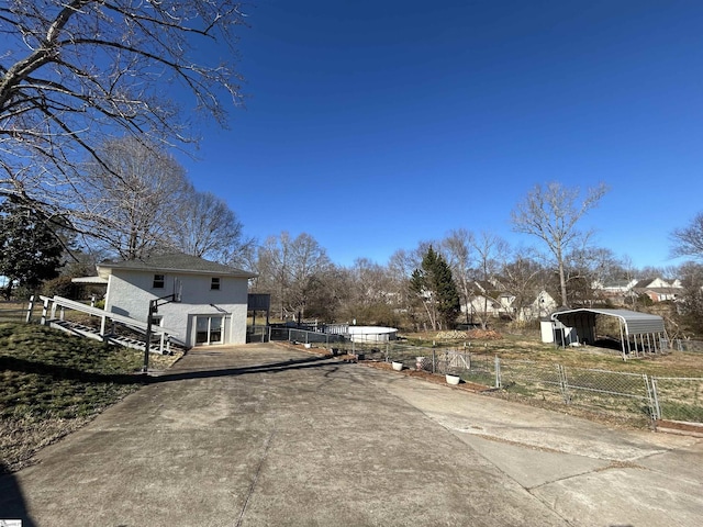 exterior space featuring driveway, fence, and a detached carport