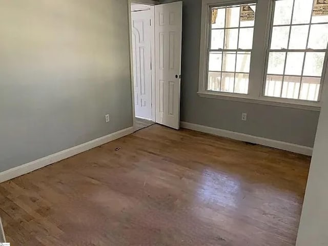 spare room with baseboards and wood finished floors