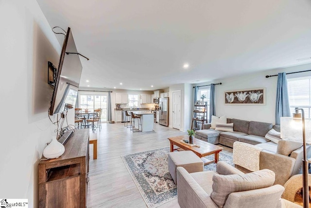 living room featuring light wood finished floors, plenty of natural light, and recessed lighting