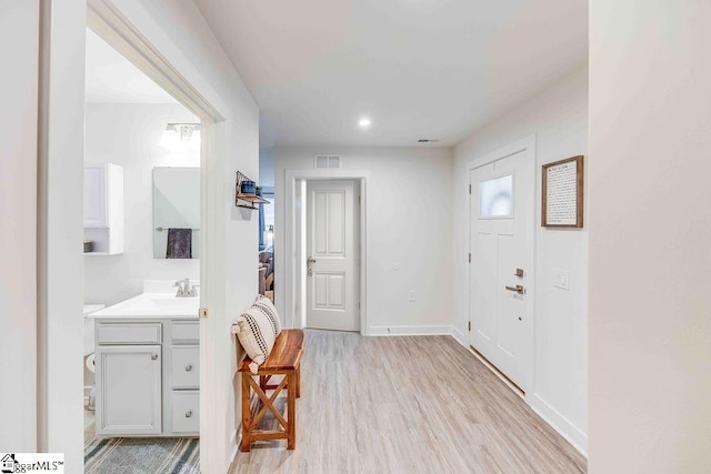 foyer entrance with light wood-type flooring, visible vents, and baseboards