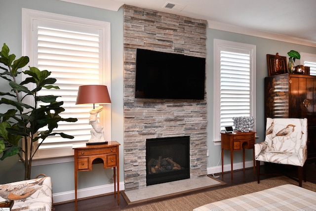 living room featuring visible vents, a stone fireplace, baseboards, and wood finished floors