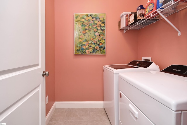 clothes washing area featuring laundry area, baseboards, washing machine and clothes dryer, and light tile patterned floors