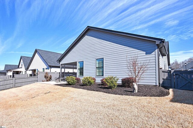 view of property exterior featuring a gate, a patio area, and fence